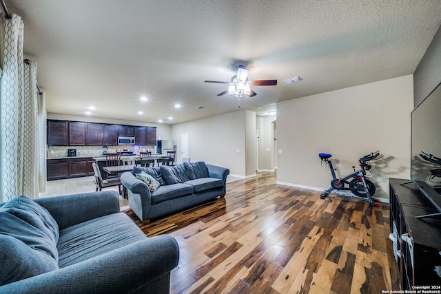 living room featuring ceiling fan, hardwood / wood-style floors, and a textured ceiling