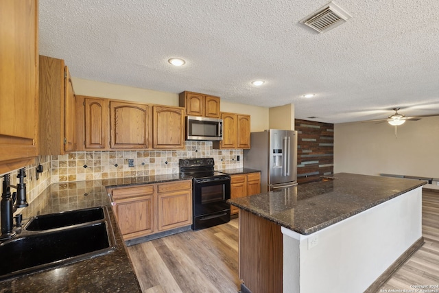 kitchen featuring sink, light hardwood / wood-style flooring, a textured ceiling, stainless steel appliances, and backsplash