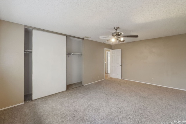 unfurnished bedroom with carpet flooring, a textured ceiling, ceiling fan, and a closet