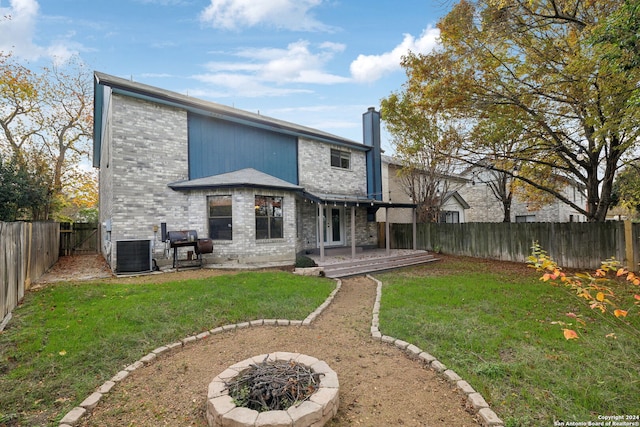 back of house featuring a yard, a patio area, central air condition unit, and a fire pit