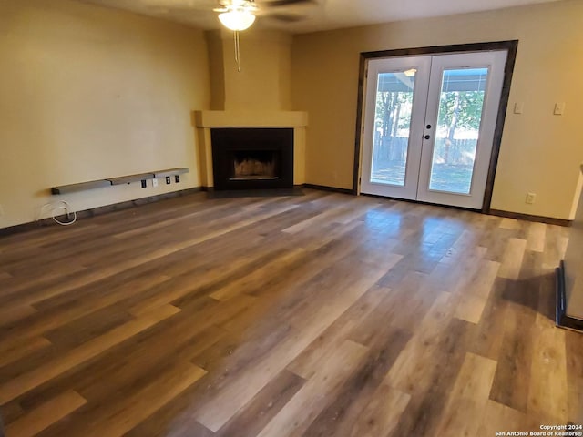 unfurnished living room featuring a large fireplace, french doors, and hardwood / wood-style flooring