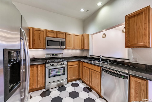 kitchen with appliances with stainless steel finishes, dark stone countertops, and sink