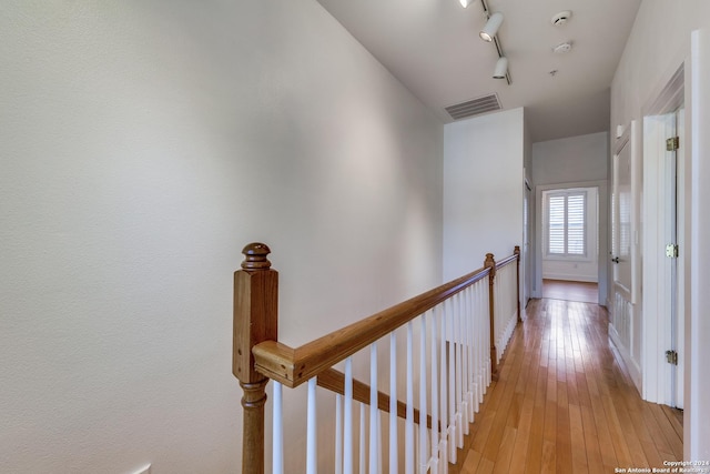 hallway with light hardwood / wood-style floors and track lighting