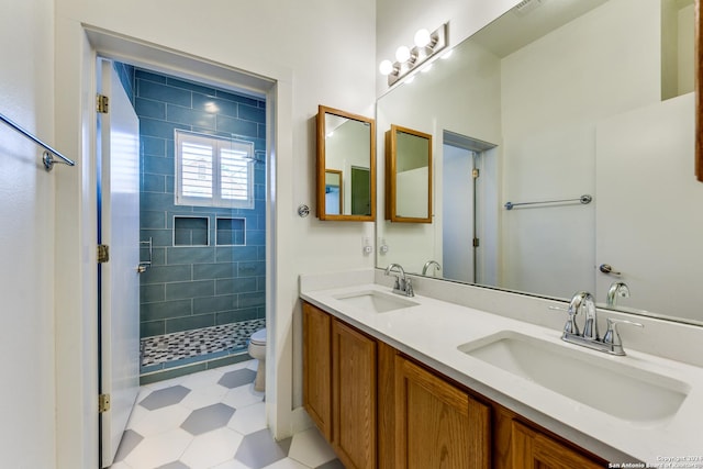 bathroom featuring a tile shower, vanity, and toilet