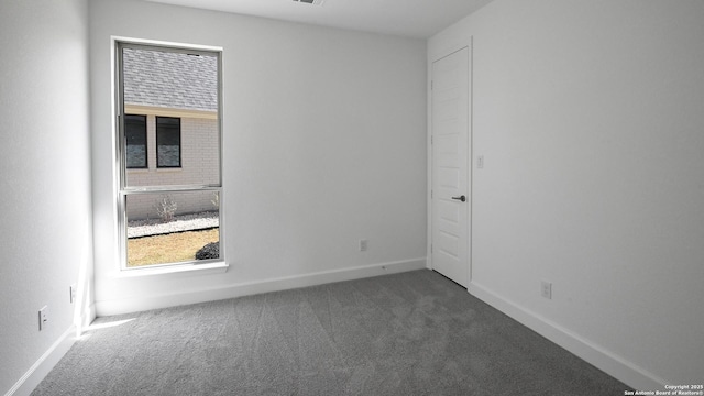 unfurnished room featuring dark colored carpet and baseboards