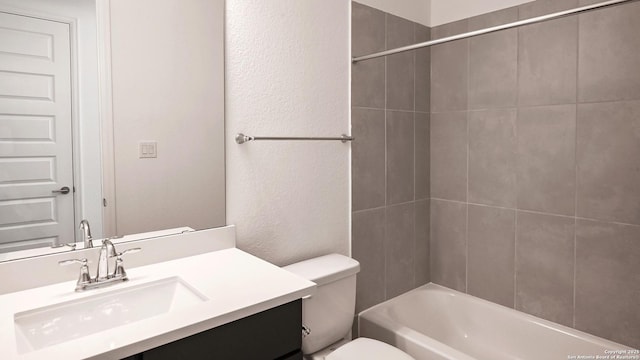 full bathroom with toilet, a textured wall, washtub / shower combination, and vanity