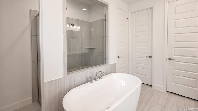 full bath featuring a freestanding bath, a shower, and baseboards