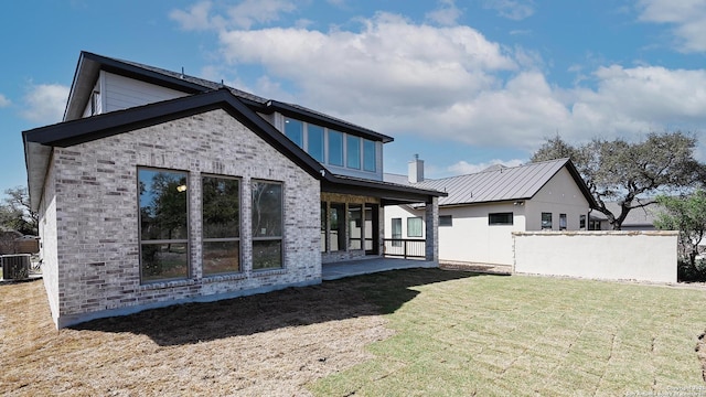 rear view of property with a patio, metal roof, a standing seam roof, cooling unit, and brick siding