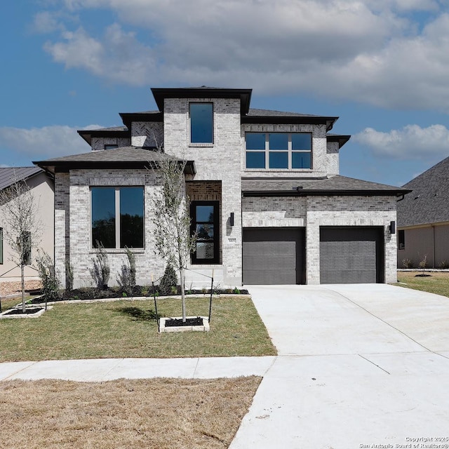 prairie-style home with an attached garage, concrete driveway, brick siding, and a front yard