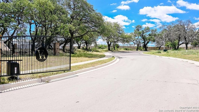 view of road featuring sidewalks, a gate, and curbs