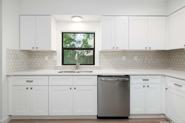 kitchen featuring decorative backsplash, stainless steel dishwasher, sink, light hardwood / wood-style floors, and white cabinetry