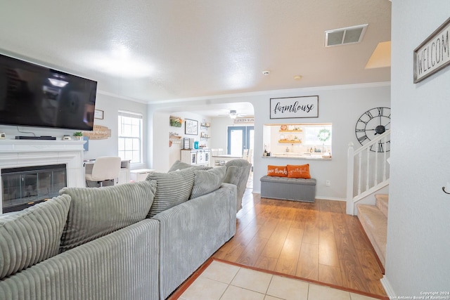 living room with a textured ceiling, ceiling fan, light hardwood / wood-style floors, and crown molding