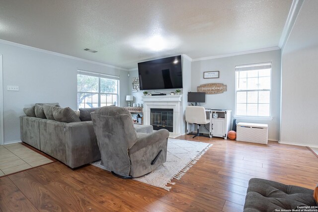 living room with hardwood / wood-style floors, ornamental molding, and a textured ceiling