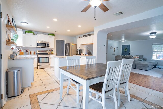 dining area with a textured ceiling, ceiling fan, sink, and light hardwood / wood-style flooring