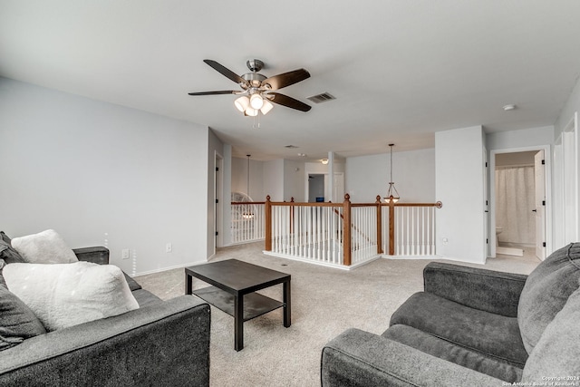 carpeted living room featuring ceiling fan with notable chandelier