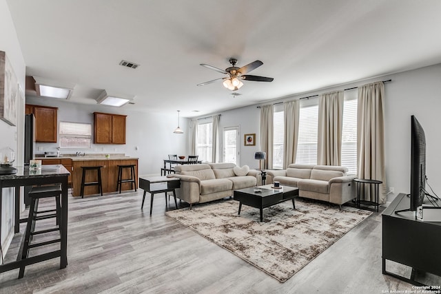 living room with ceiling fan and light hardwood / wood-style flooring