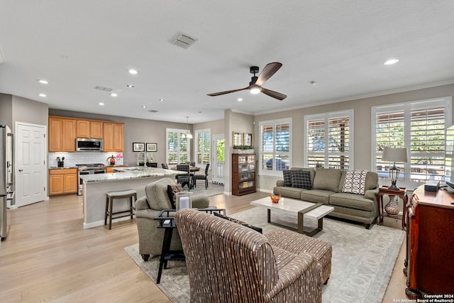 living room with plenty of natural light, ceiling fan, ornamental molding, and light hardwood / wood-style flooring