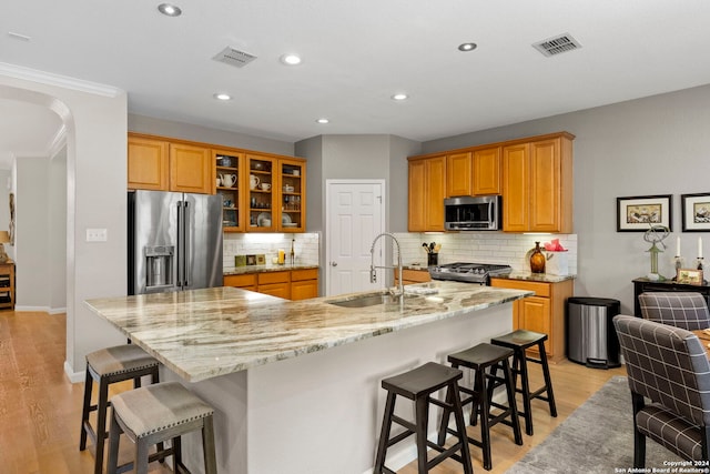 kitchen with a spacious island, light stone countertops, stainless steel appliances, and light hardwood / wood-style flooring