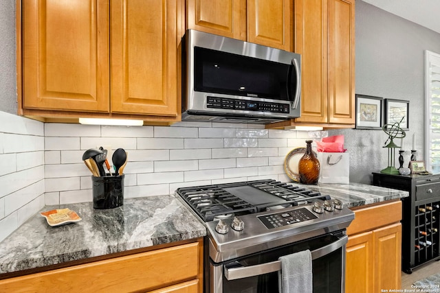 kitchen with backsplash, dark stone countertops, and appliances with stainless steel finishes