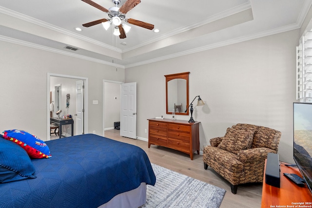 bedroom featuring a raised ceiling, crown molding, ceiling fan, and light wood-type flooring