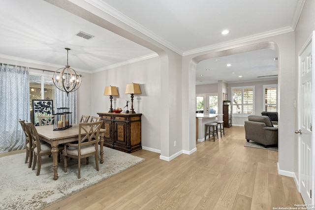 dining area featuring crown molding, a chandelier, and light wood-type flooring