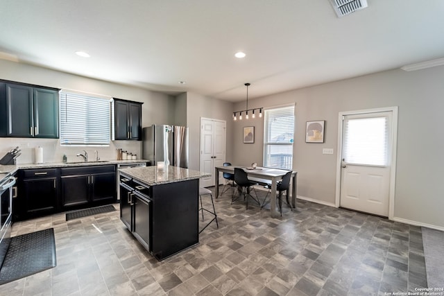 kitchen with decorative backsplash, stainless steel fridge, a breakfast bar, a center island, and hanging light fixtures