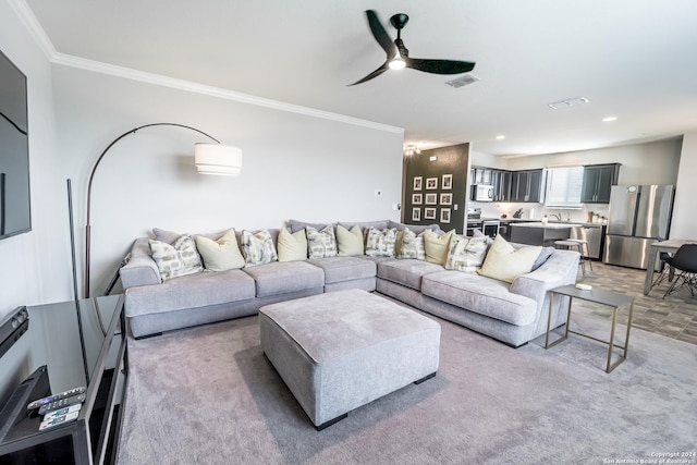 carpeted living room with ceiling fan and crown molding