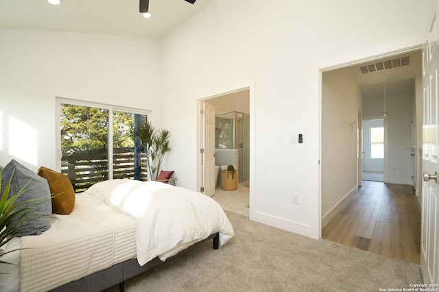 bedroom featuring ensuite bathroom, access to outside, ceiling fan, high vaulted ceiling, and light hardwood / wood-style floors