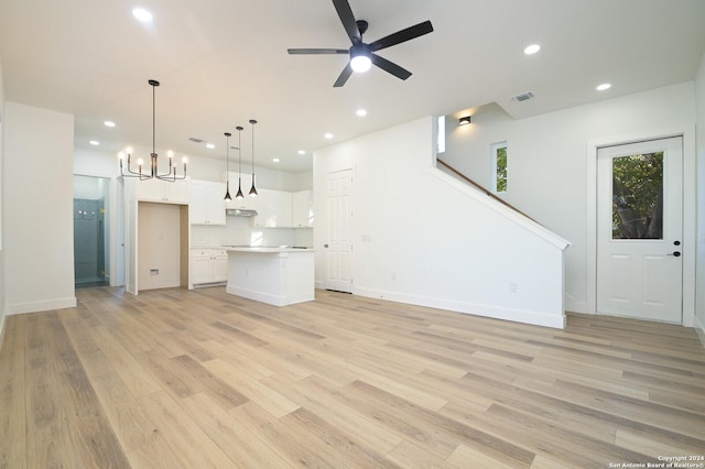 unfurnished living room with light hardwood / wood-style flooring and ceiling fan with notable chandelier