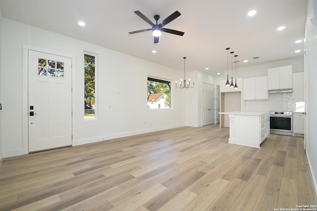 kitchen featuring electric stove, white cabinets, light hardwood / wood-style floors, a kitchen island, and hanging light fixtures