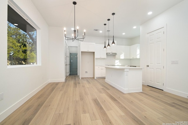 kitchen with white cabinetry, a center island, decorative light fixtures, and light wood-type flooring