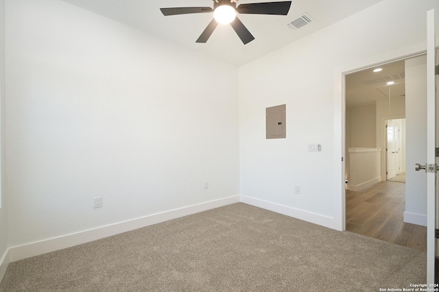 empty room with hardwood / wood-style floors, electric panel, and ceiling fan