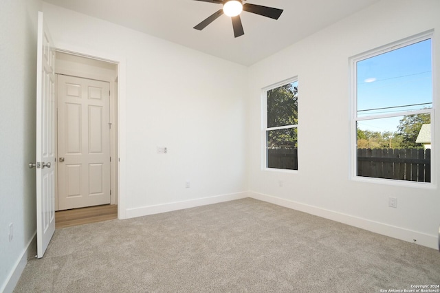 empty room featuring ceiling fan and light colored carpet