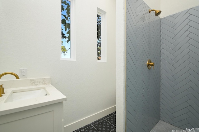 bathroom with tile patterned floors, vanity, and tiled shower