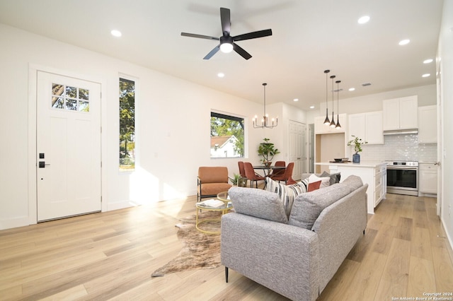 living room featuring ceiling fan with notable chandelier and light wood-type flooring