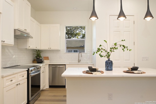 kitchen with light stone counters, sink, stainless steel appliances, and decorative light fixtures