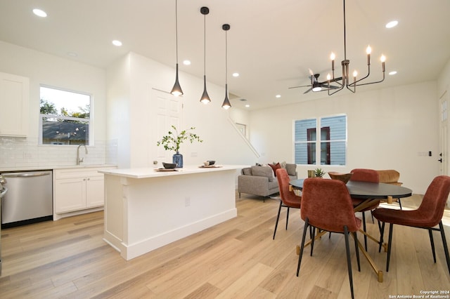 dining area featuring ceiling fan with notable chandelier, light hardwood / wood-style floors, and sink