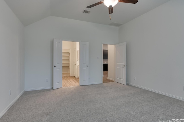 unfurnished bedroom featuring light carpet, a walk in closet, ceiling fan, high vaulted ceiling, and a closet