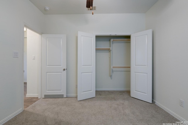 unfurnished bedroom with ceiling fan, a closet, and light colored carpet