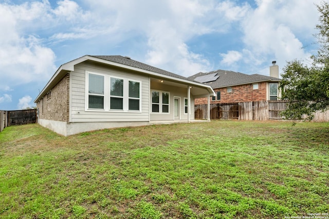 rear view of property featuring a lawn