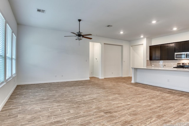 kitchen featuring tasteful backsplash, dark brown cabinetry, stainless steel appliances, and light wood-type flooring