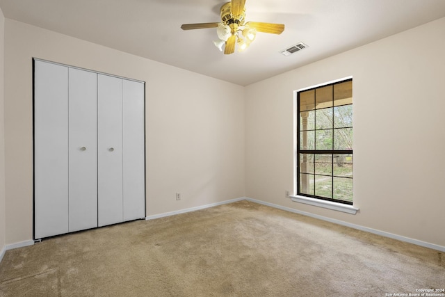 unfurnished bedroom featuring ceiling fan, light colored carpet, and a closet