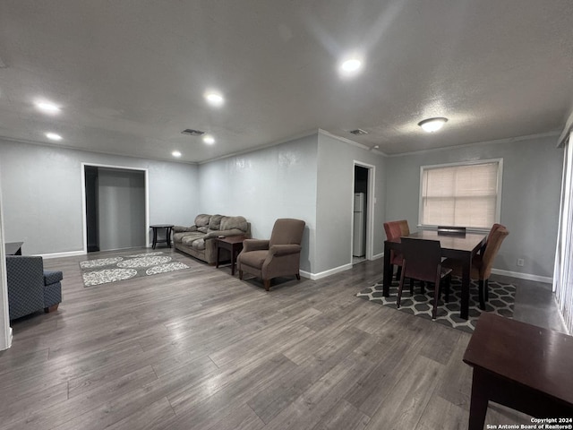 living room featuring crown molding, wood-type flooring, and a textured ceiling