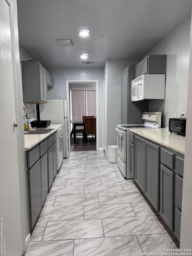 kitchen with gray cabinetry, white appliances, and sink