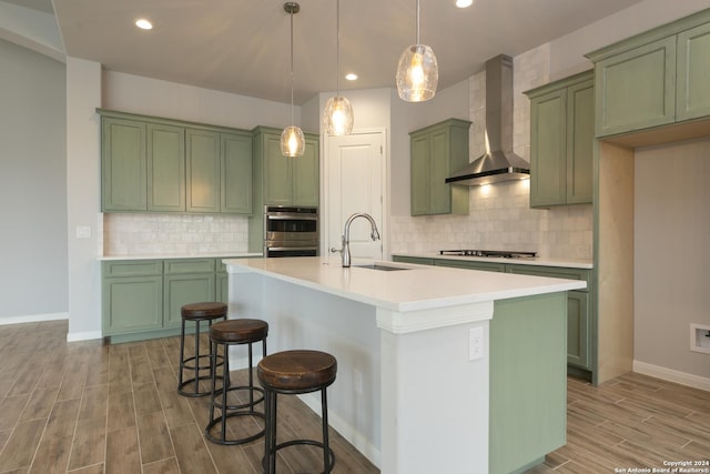 kitchen with pendant lighting, wall chimney exhaust hood, sink, and green cabinetry