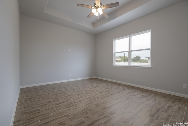 unfurnished room featuring a tray ceiling, ceiling fan, and hardwood / wood-style floors