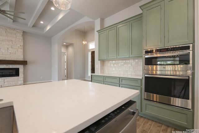 kitchen featuring dark wood-type flooring, green cabinets, double oven, decorative light fixtures, and decorative backsplash