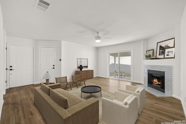 living room with a fireplace, wood-type flooring, and ceiling fan