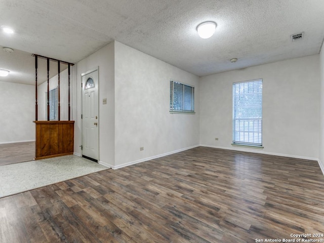 unfurnished room with dark wood-type flooring and a textured ceiling