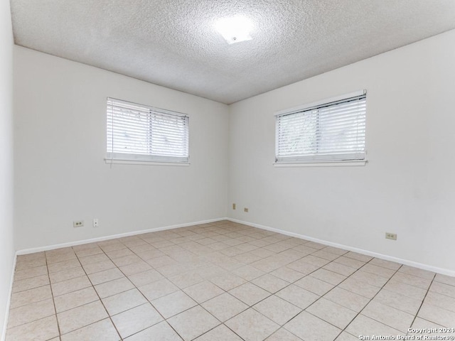 tiled empty room with a textured ceiling